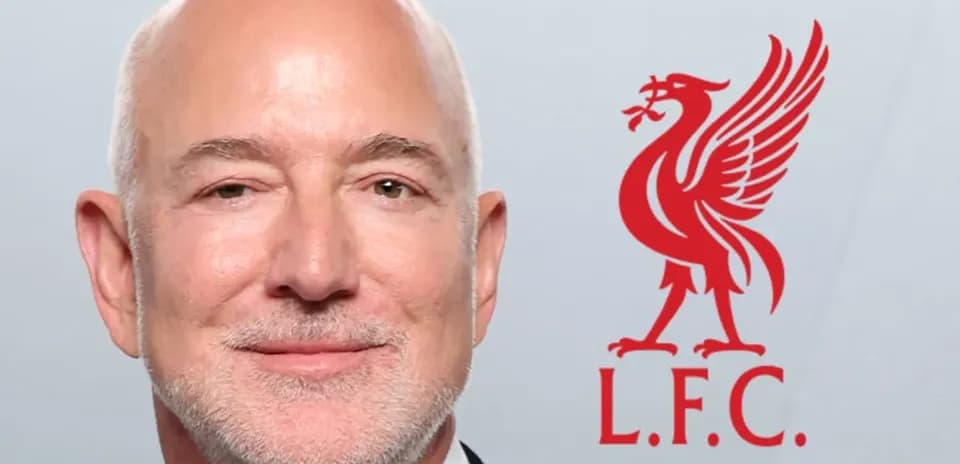 Man in suit with Liverpool FC logo background
