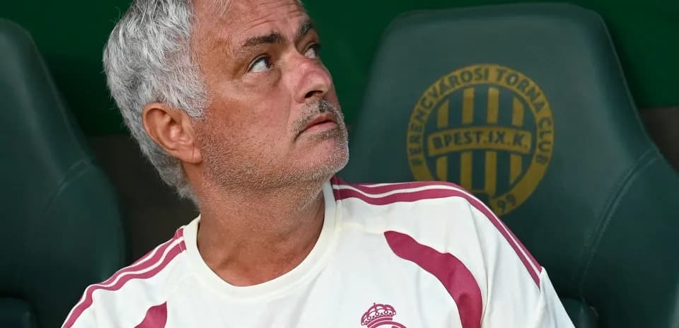 Coach sitting on bench during match, looking up