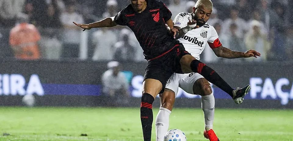 Player tackling opponent during a rainy football match