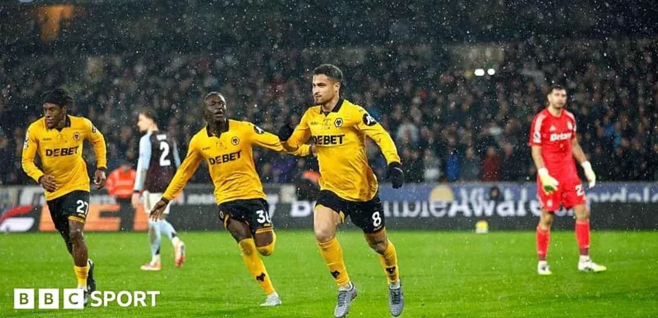 Player celebrating goal with teammates in rain