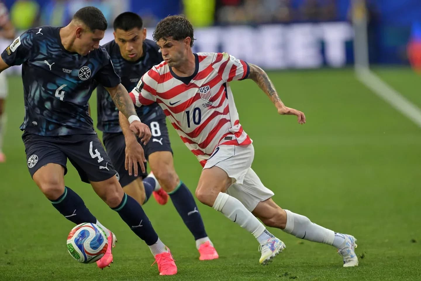 Christian Pulisic dribbling past opposing players