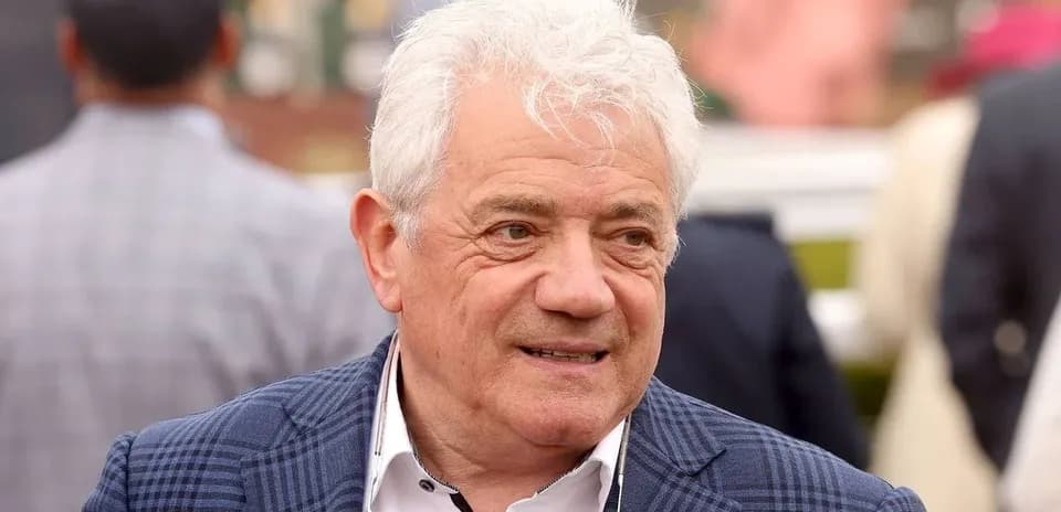 Man with white hair in a checkered blazer