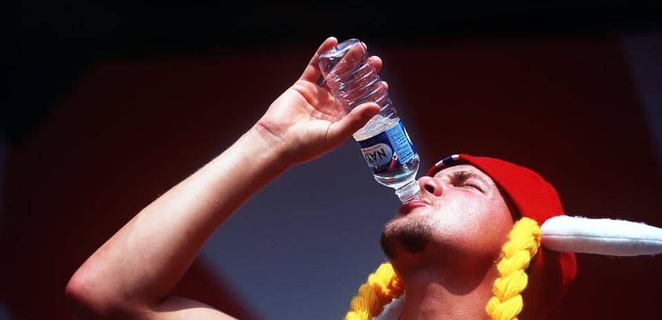 Person drinking water from a bottle outdoors