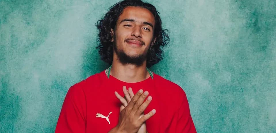 Player posing in red jersey with clasped hands