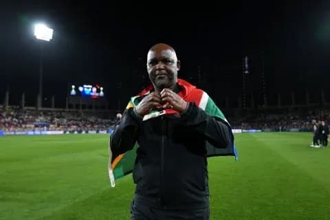 Coach wearing South African flag on shoulders at stadium