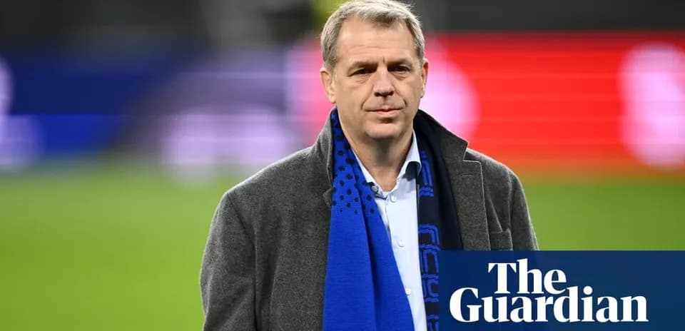 Man in coat and scarf on football pitch