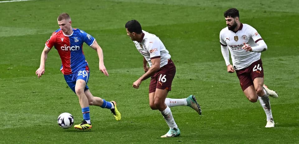 Player in red and blue kit dribbling past two opponents