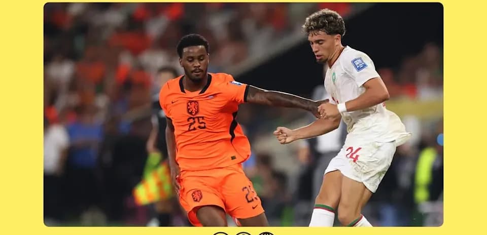 Player in orange and player in white battling for the ball