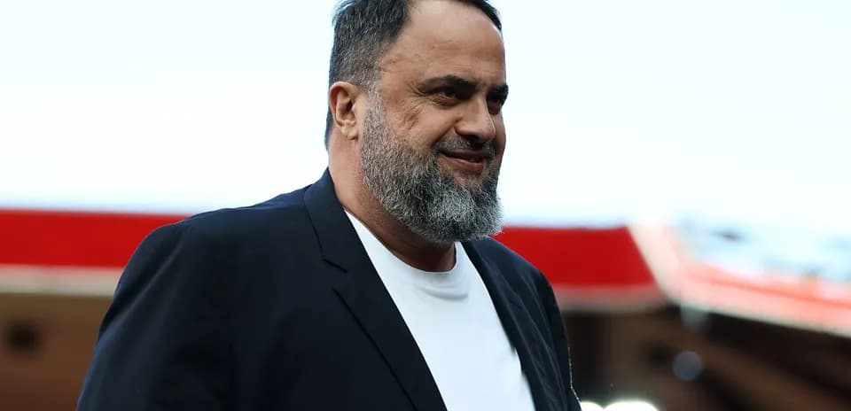 Man in a black blazer smiling outdoors