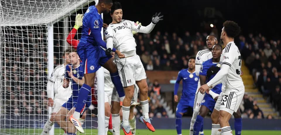 Chelsea player challenging Fulham goalkeeper during match