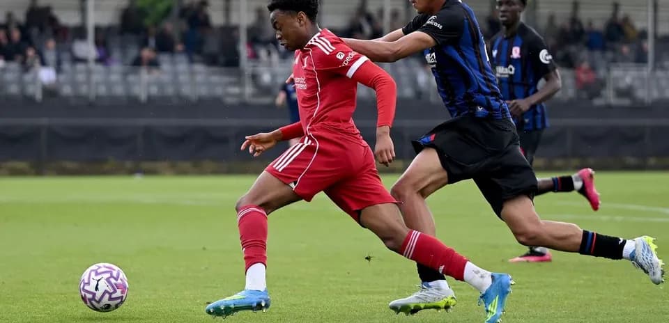 Player in red dribbling past opponent in blue