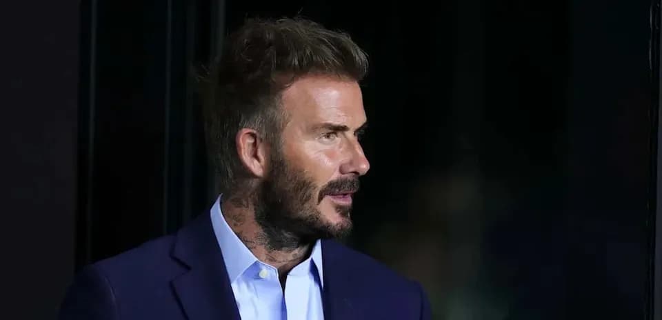 Man in suit with tattoos speaking off-camera
