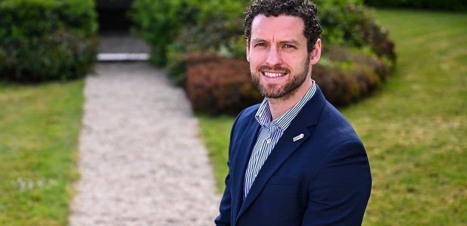 Man in suit standing on gravel pathway outdoors