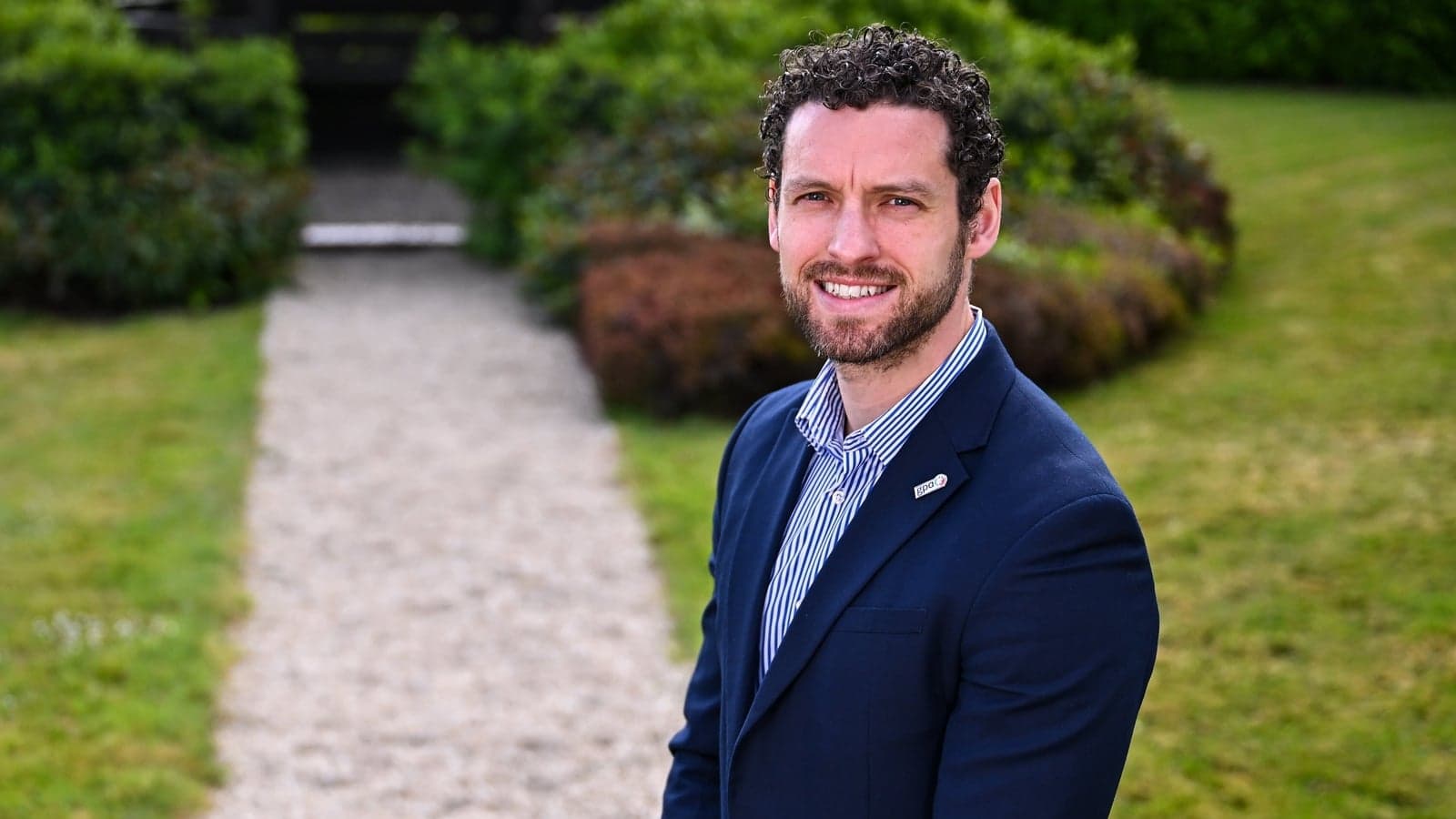 Man in suit standing on gravel pathway outdoors