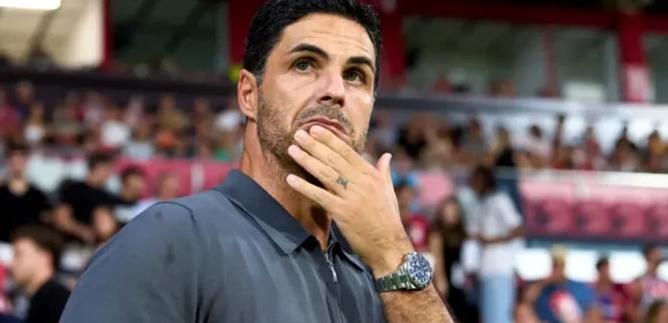Coach observing match from sidelines with fans behind