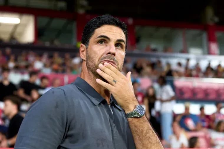 Coach observing match from sidelines with fans behind