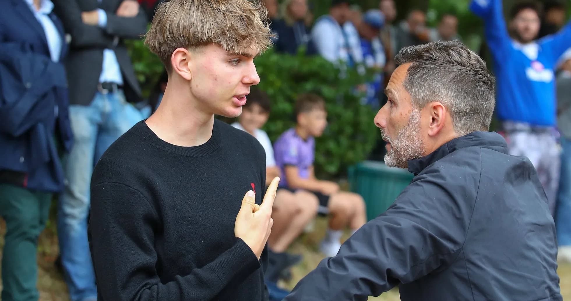 Two men engaged in discussion near spectators