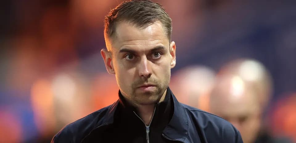 Man in dark jacket walking on sports field