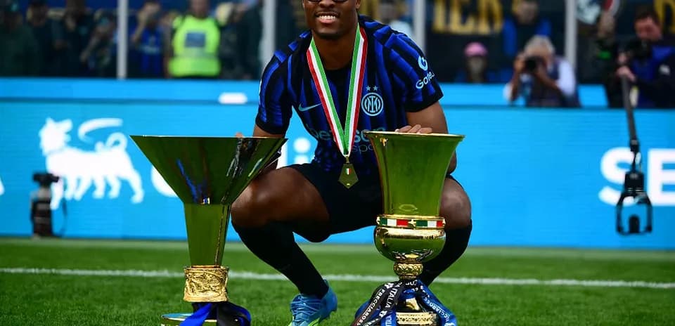 Player celebrating with two trophies on the field