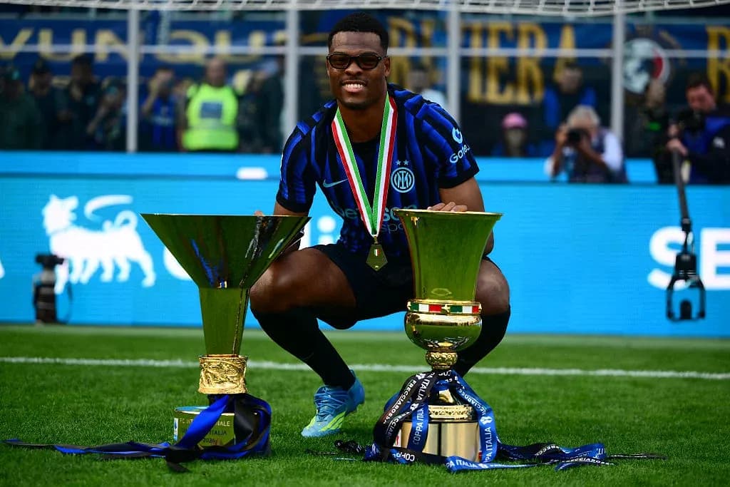 Player celebrating with two trophies on the field