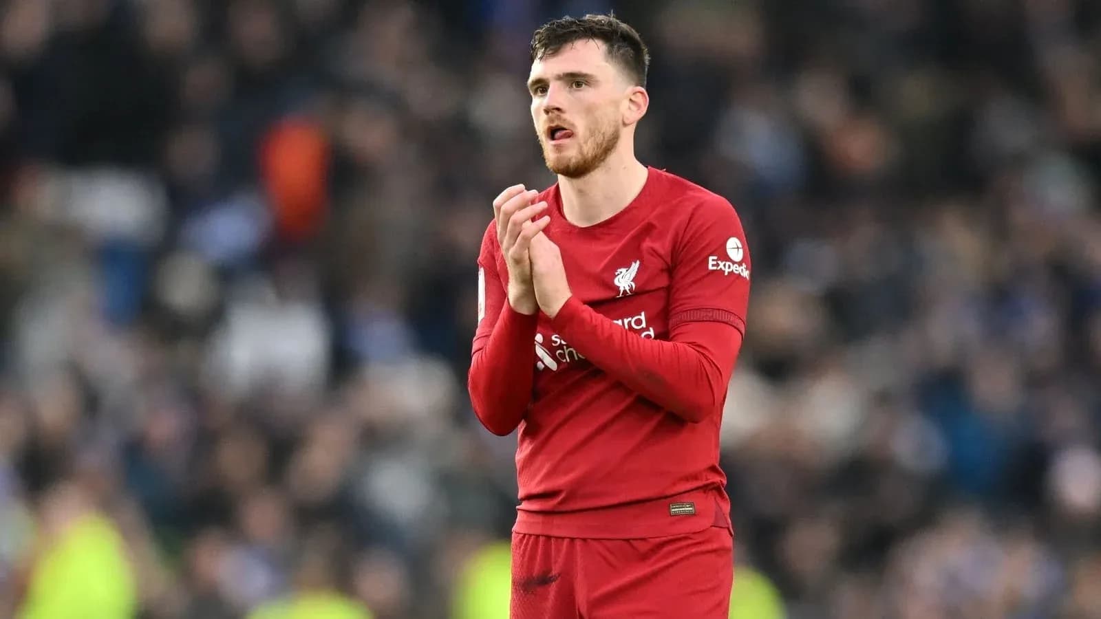 Player in red jersey applauding fans after match