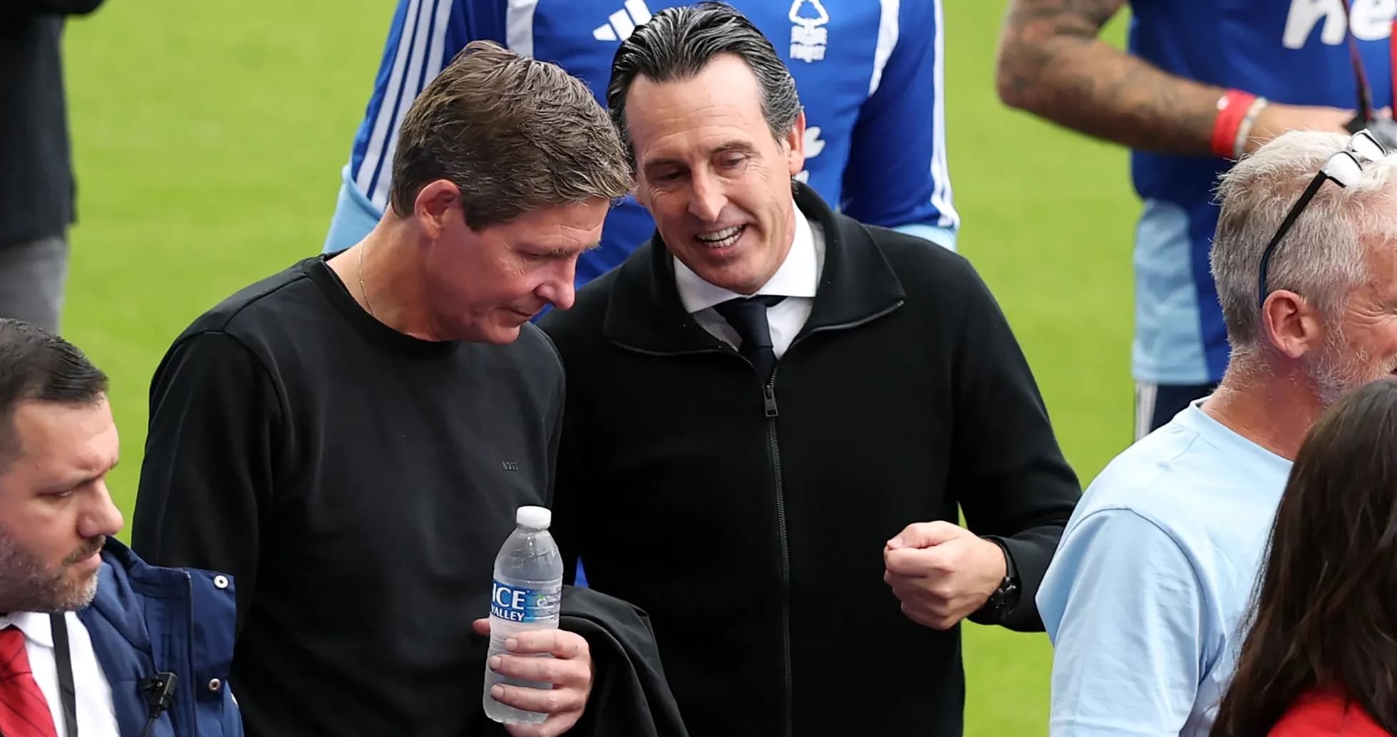 Two men conversing near football pitch