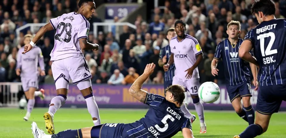Player in purple kit shooting while defender falls
