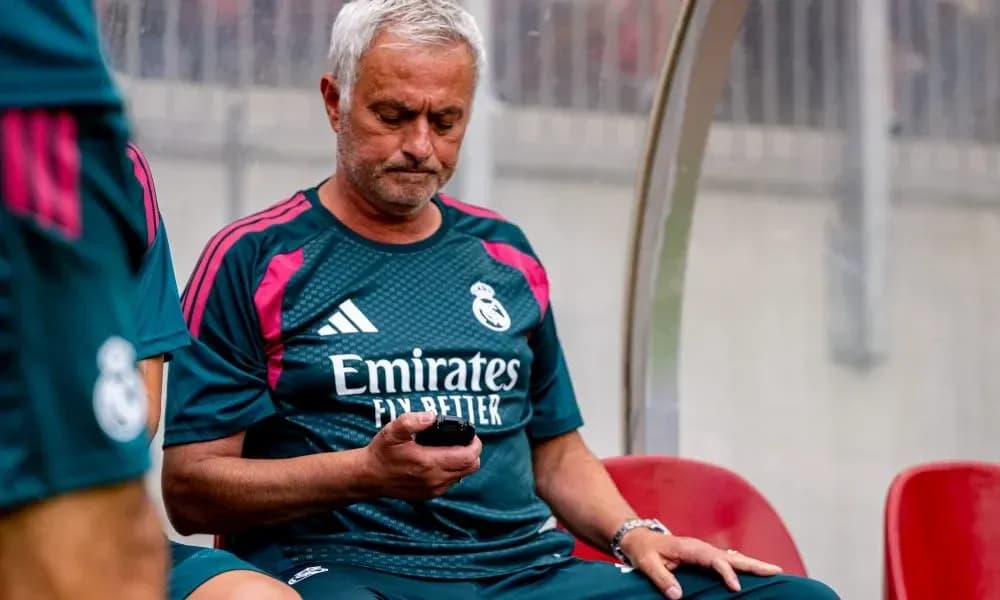 Coach checking phone while seated on bench Coach checking phone while seated on bench