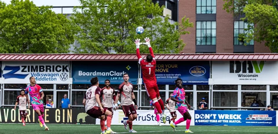 Goalkeeper jumping to catch the ball during match