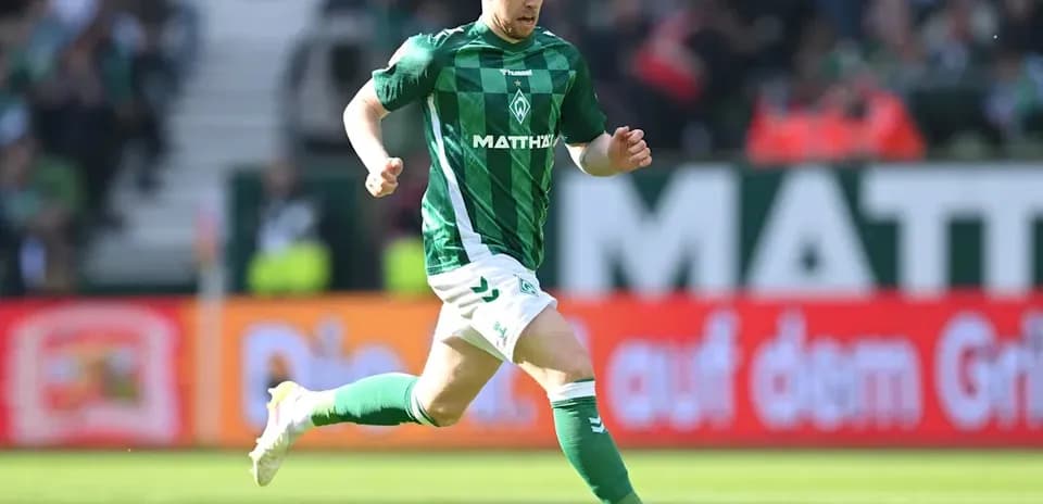 Player in green jersey running with soccer ball