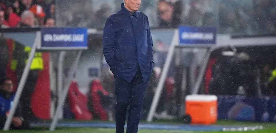 Coach standing on sideline during rainy match