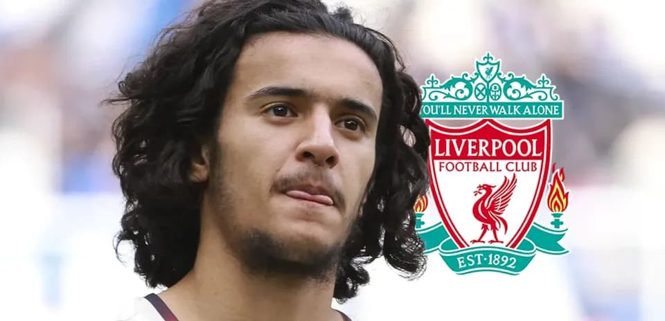 Player with long hair in front of Liverpool logo