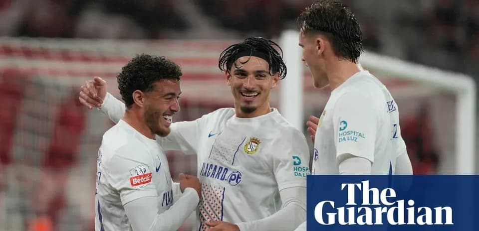 Three football players celebrating a goal together