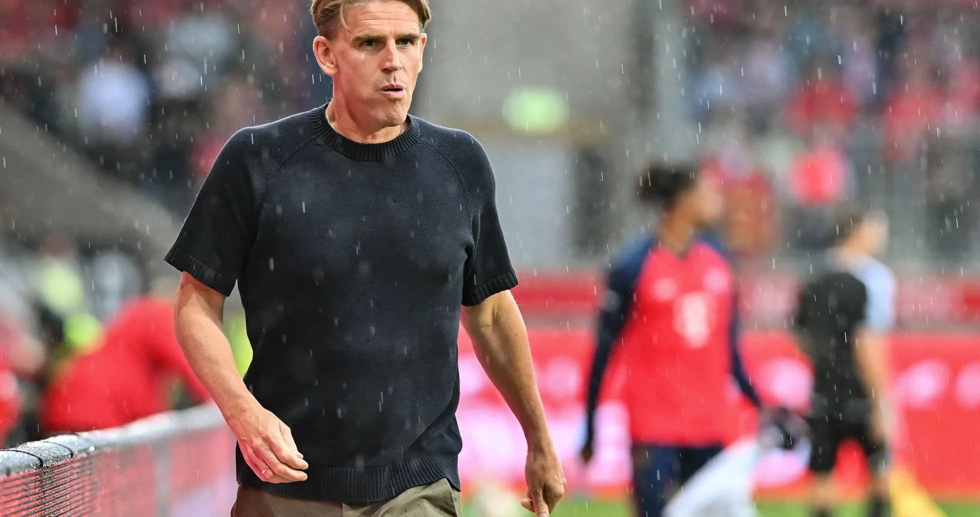 Coach walking along the sideline in the rain Coach walking along the sideline in the rain