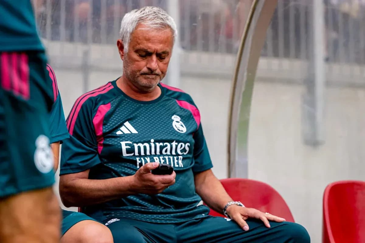 Coach seated on bench looking at mobile phone Coach seated on bench looking at mobile phone