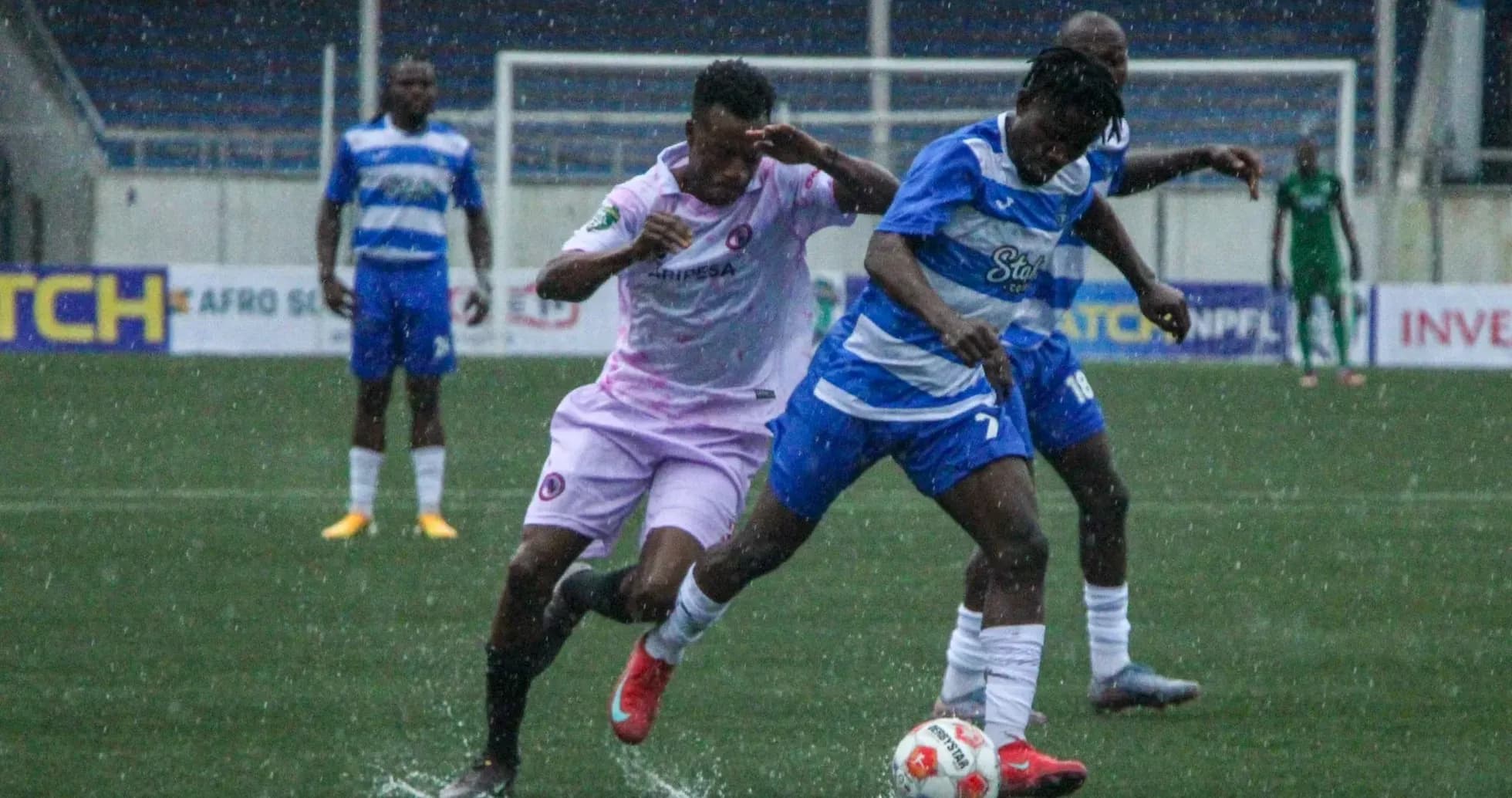 Players competing for the ball in rainy match Players competing for the ball in rainy match
