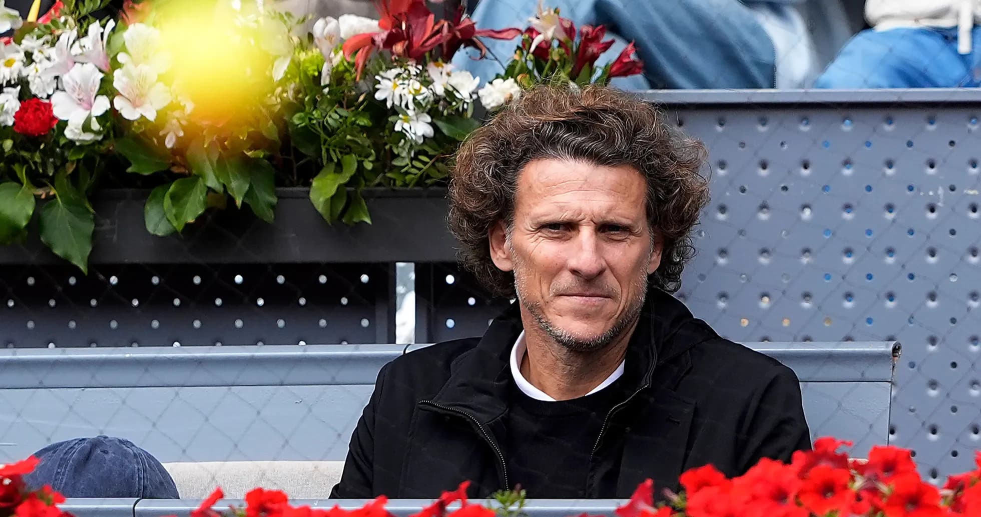 Person sitting among flowers at a tennis event Person sitting among flowers at a tennis event