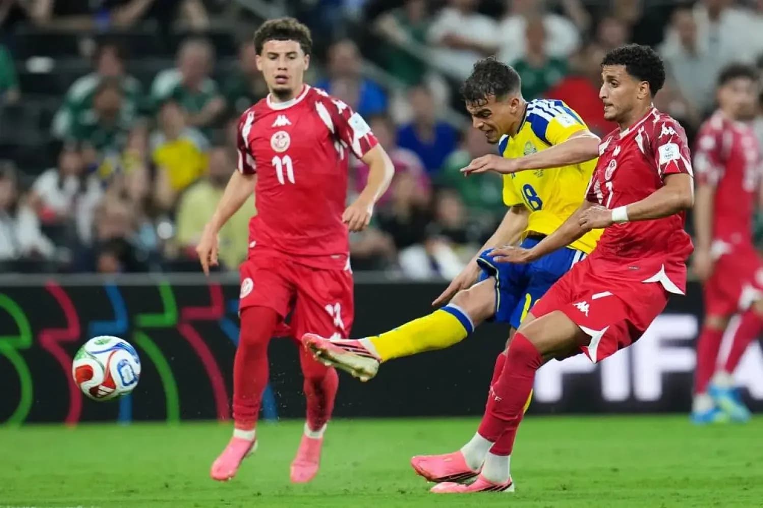 Sweden player shooting while two Tunisia defenders approach Sweden player shooting while two Tunisia defenders approach