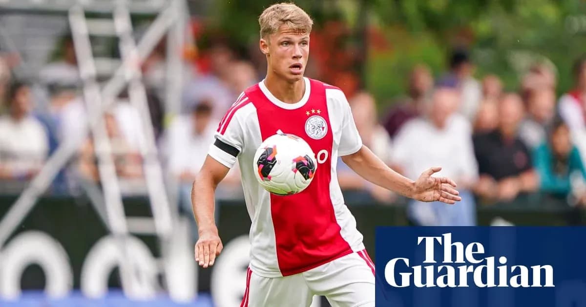 Player in Ajax kit controlling ball during match Player in Ajax kit controlling ball during match