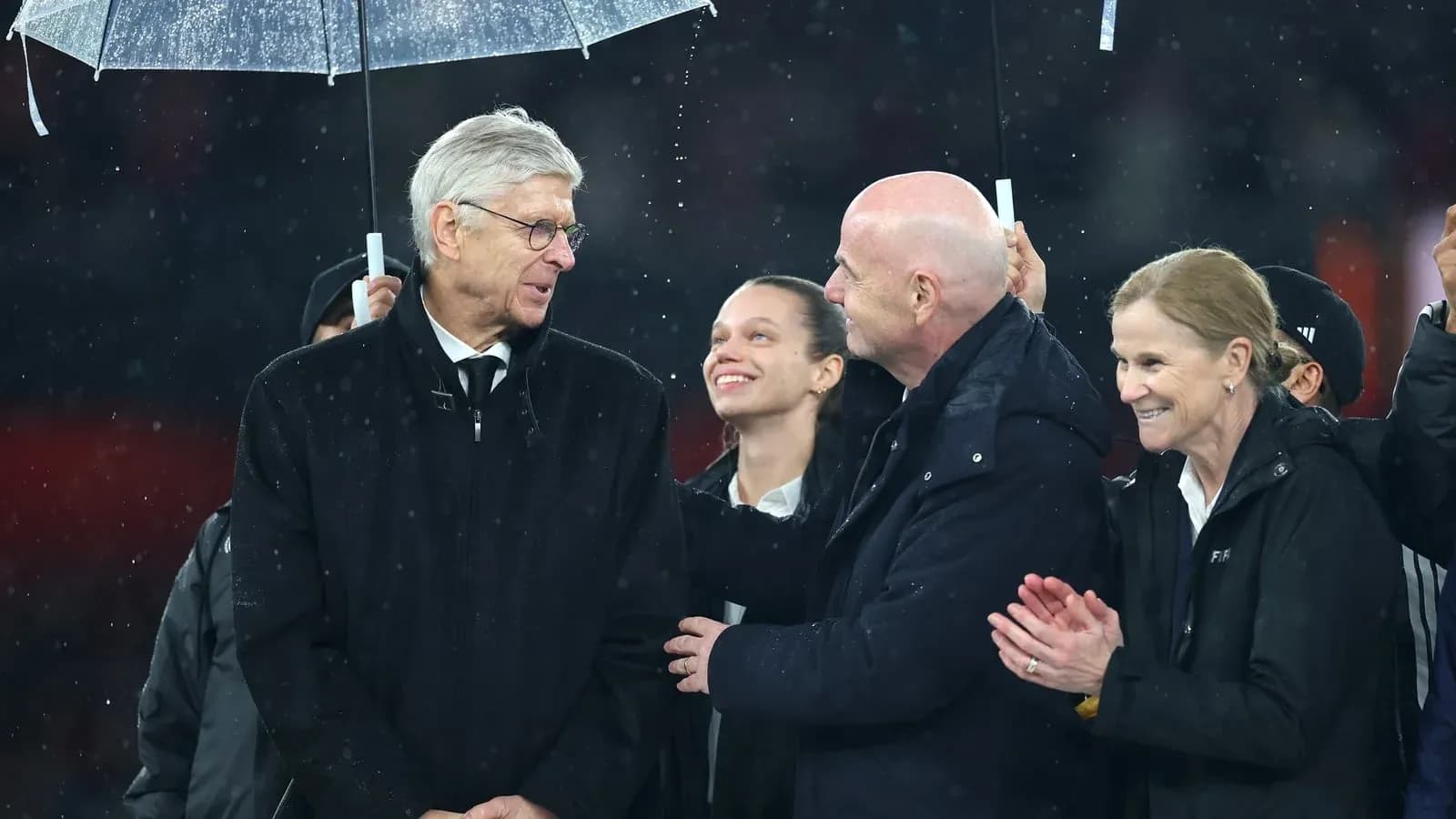 Group of officials speaking under an umbrella in rain Group of officials speaking under an umbrella in rain