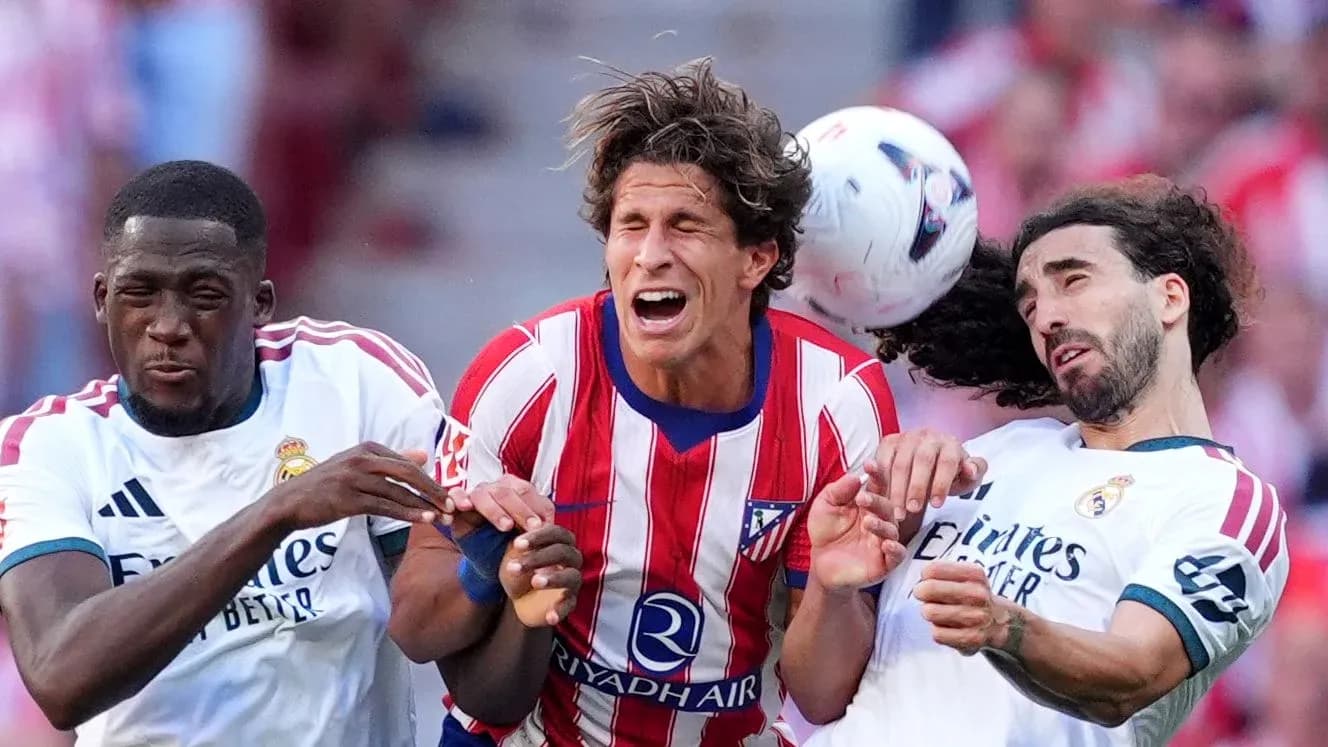 Players from Atlético and Real Madrid contesting a header Players from Atlético and Real Madrid contesting a header