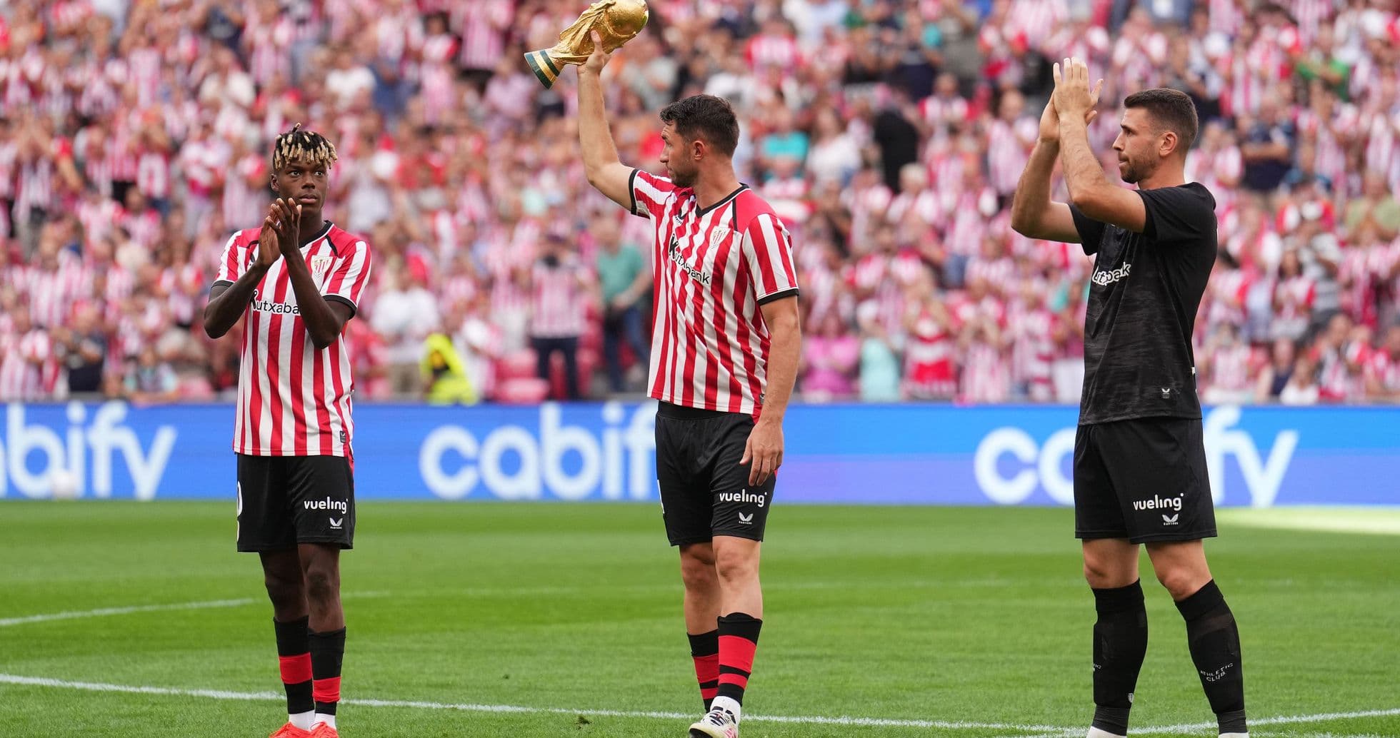 Player holding trophy with teammates applauding fans Player holding trophy with teammates applauding fans