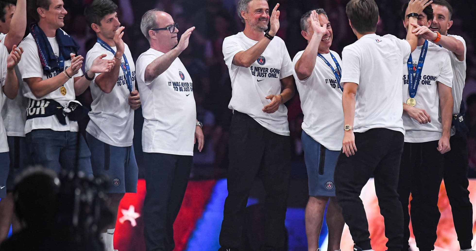 Team celebrating with T-shirts and medals on stage Team celebrating with T-shirts and medals on stage