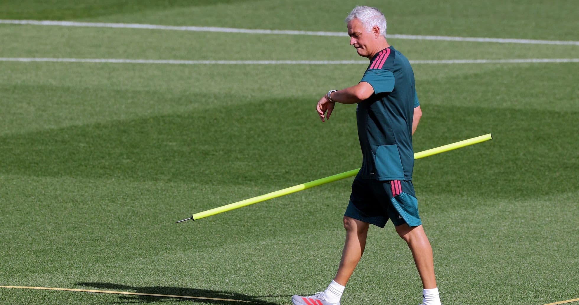 Coach walking with training pole on pitch Coach walking with training pole on pitch