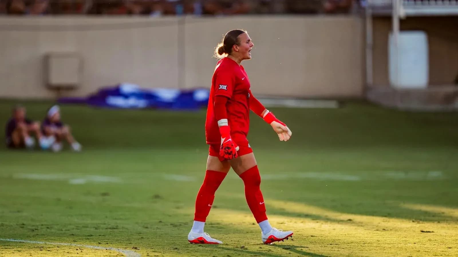 Goalkeeper in red uniform walking on field Goalkeeper in red uniform walking on field