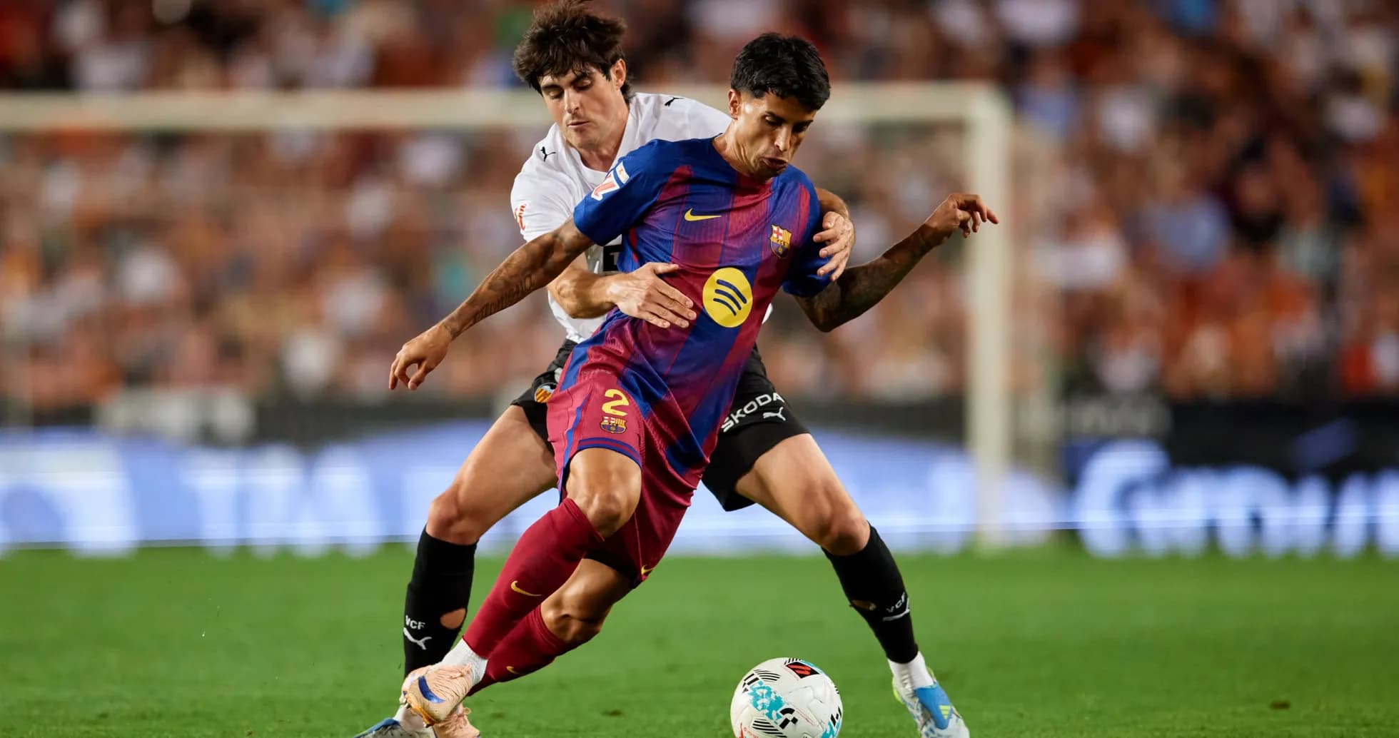 Barcelona player challenged by Valencia player during match Barcelona player challenged by Valencia player during match