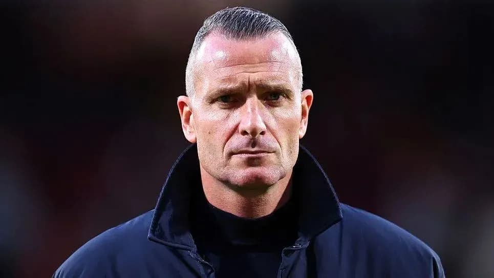 Man in dark coat standing on football pitch Man in dark coat standing on football pitch