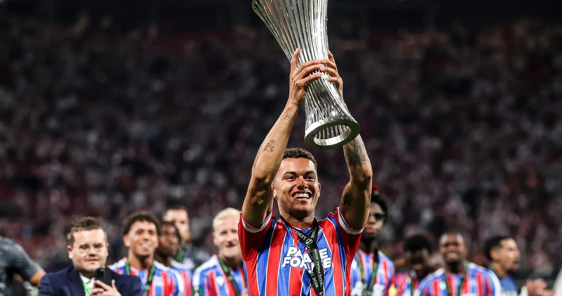 Player celebrating with trophy and teammates in stadium Player celebrating with trophy and teammates in stadium