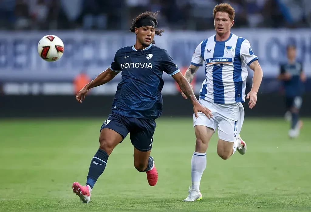 Player in blue chasing ball with opponent nearby Player in blue chasing ball with opponent nearby