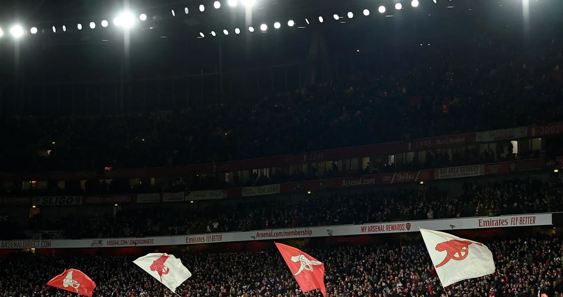 Arsenal fans waving flags in stadium crowd Arsenal fans waving flags in stadium crowd